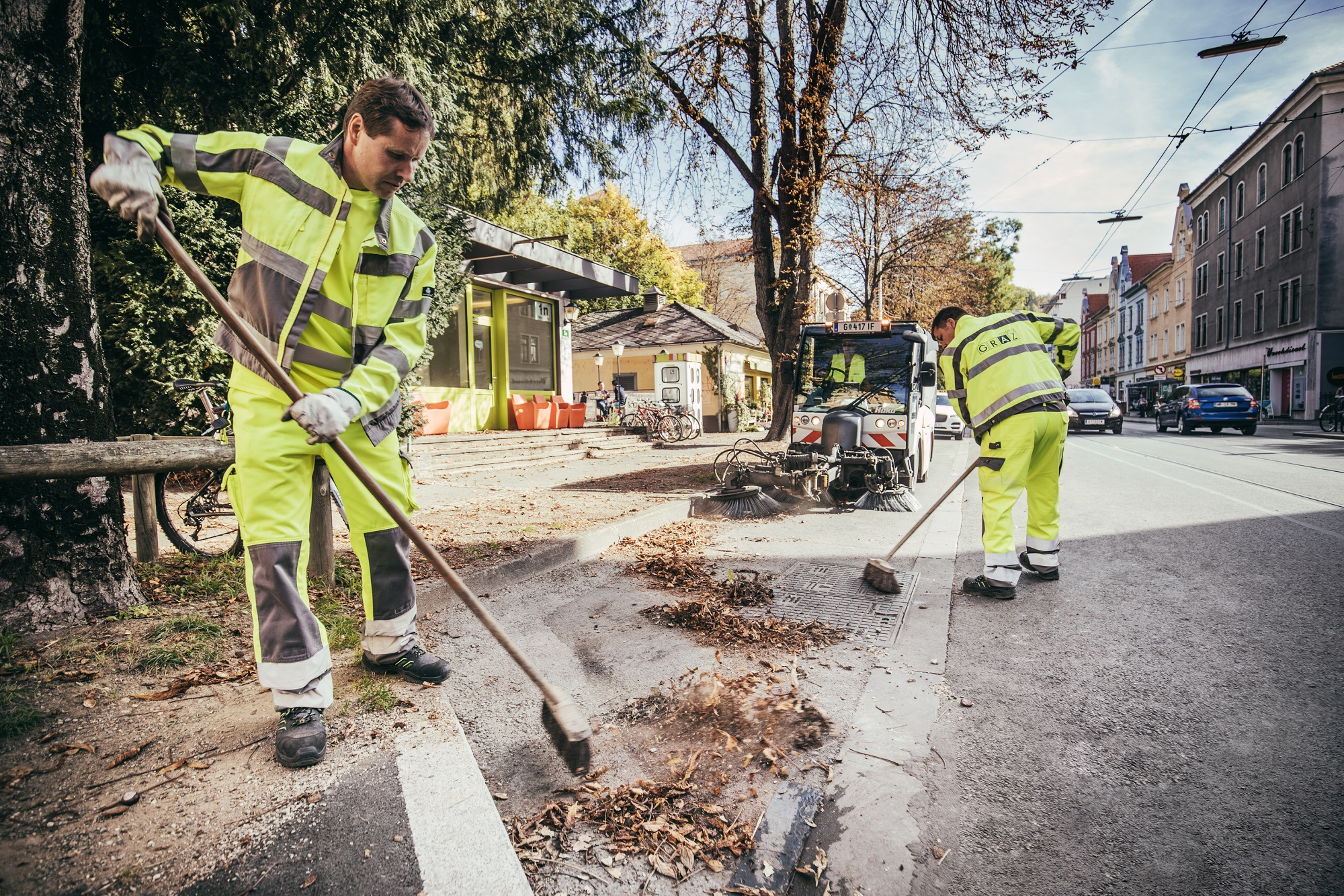 City cleaning employees clean the side of the road by hand.